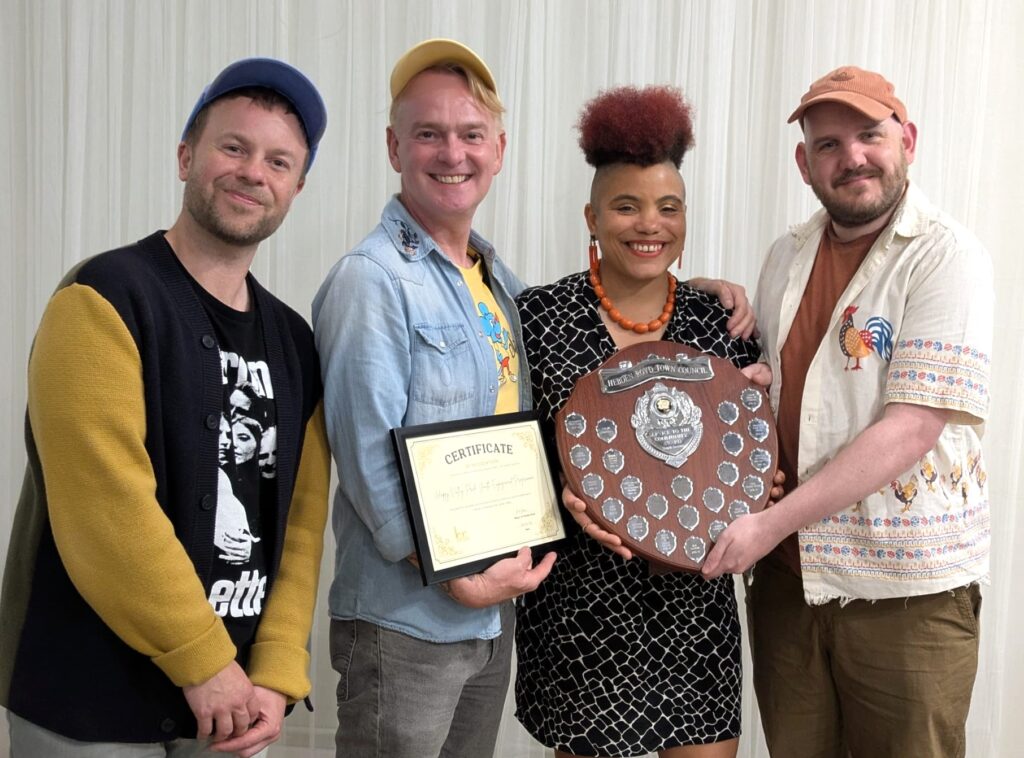 Happy Valley Pride members holding their certificate and award for the Youth Section of the Service to the Community Award.