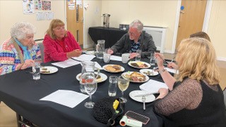 Cllr. Keith Butterick joins four other judges around a table, deciding on the 2026 World Dock Pudding Champions.