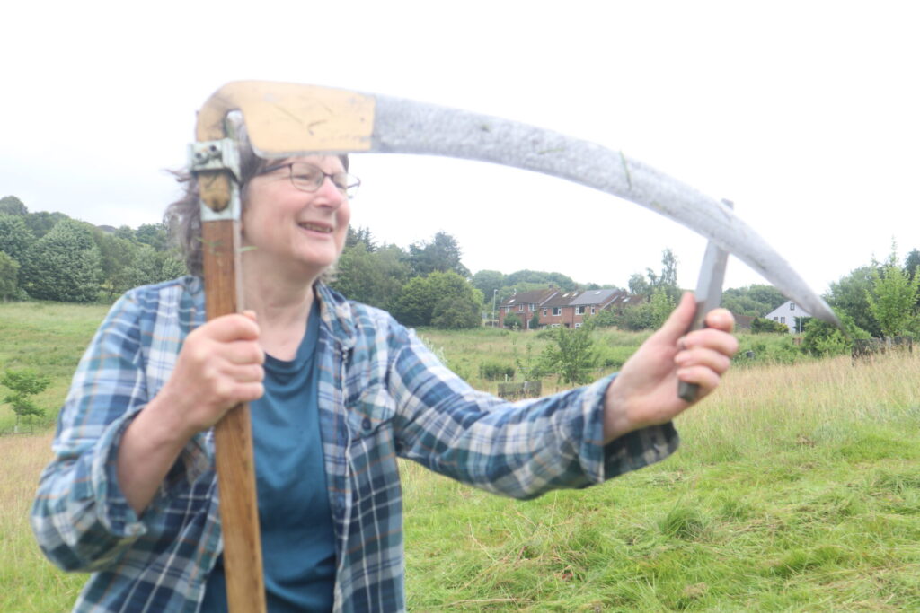 A volunteer sharpening scythe before the scything demonstration on Meadows Day 2026